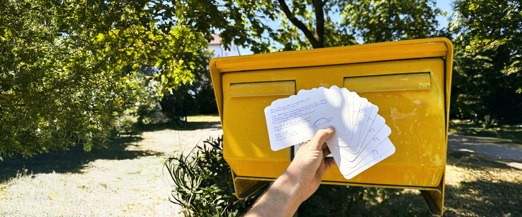 Handgeschriebene Postkarten werden am Briefkasten aufgefächert, bevor sie eingeworfen werden