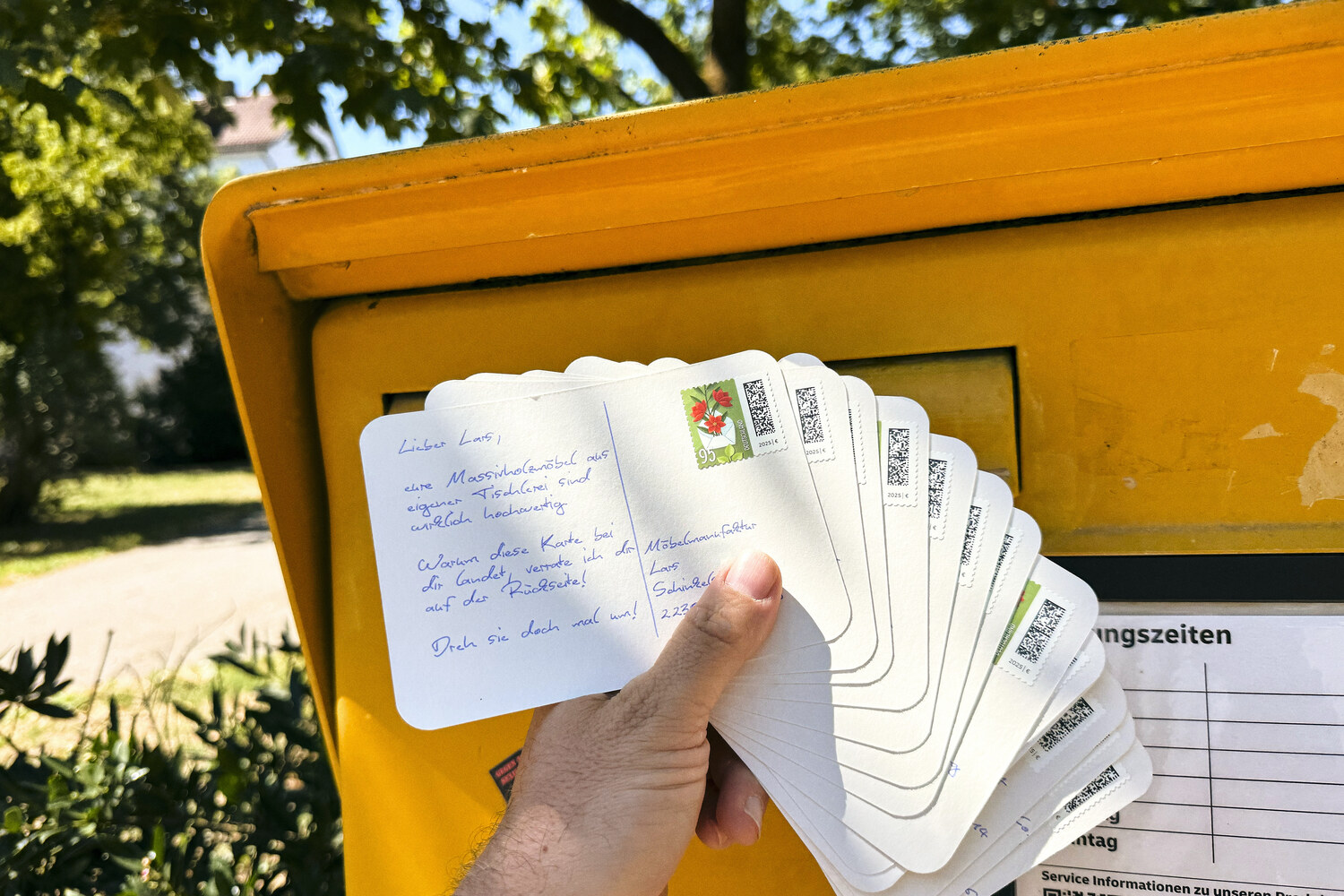 Handgeschriebene Postkarten am Briefkasten aufgefächert, bereit zum Versand