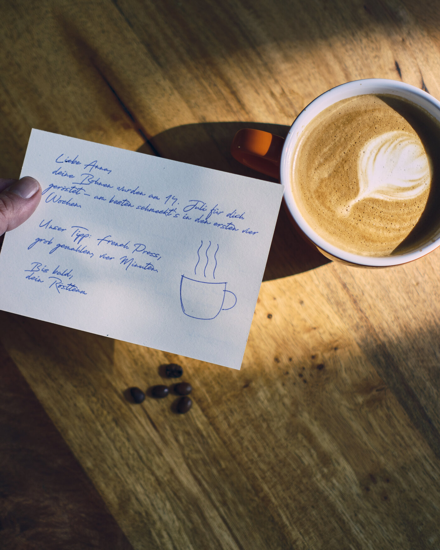 Handgeschriebene Dankeskarte neben einer Tasse Kaffee mit Latte-Art — Kundenbindung im E-Commerce