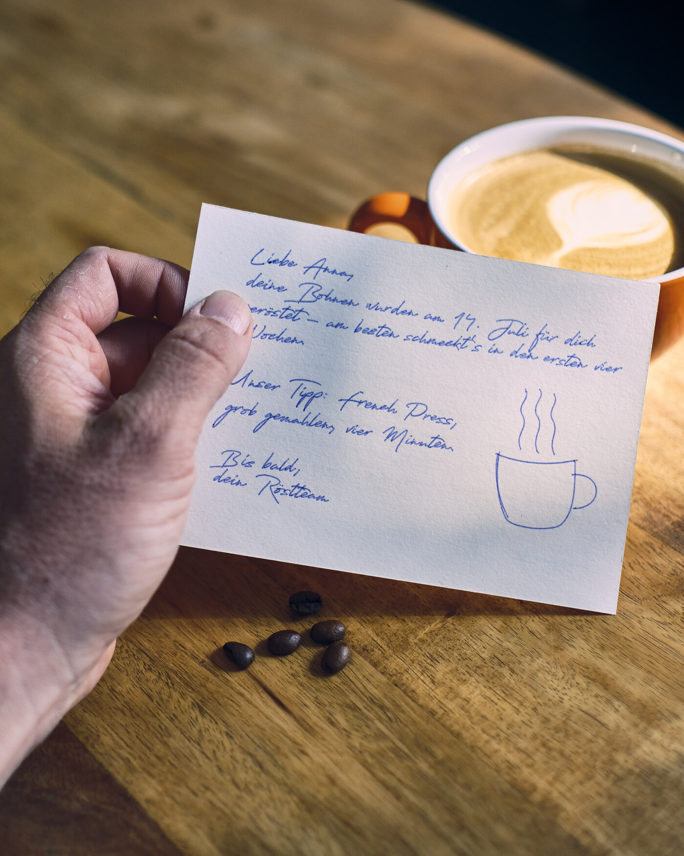 Handgeschriebene Dankeskarte für einen Kaffee-Onlineshop mit Röstdatum und Zubereitungstipp, in der Hand gehalten
