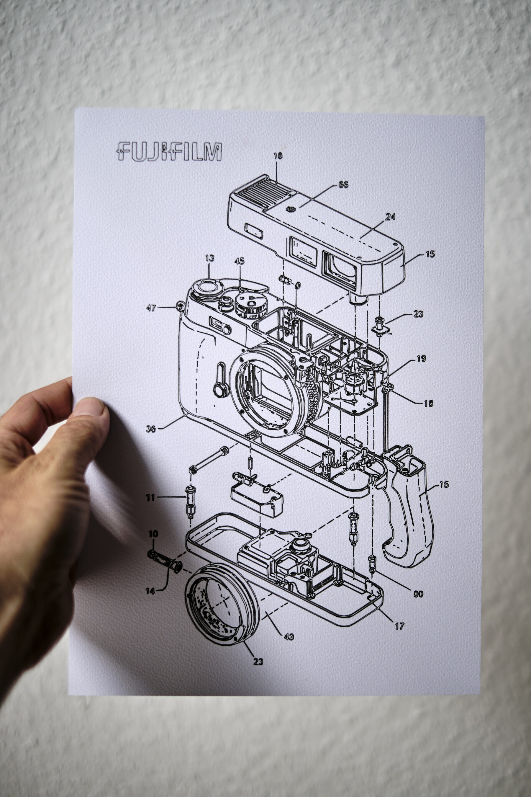 Explosionszeichnung einer Kamera mit Bauteil-Nummerierung, in der Hand gehalten — Beispiel für technische Produkt-Illustration als Kundengeschenk