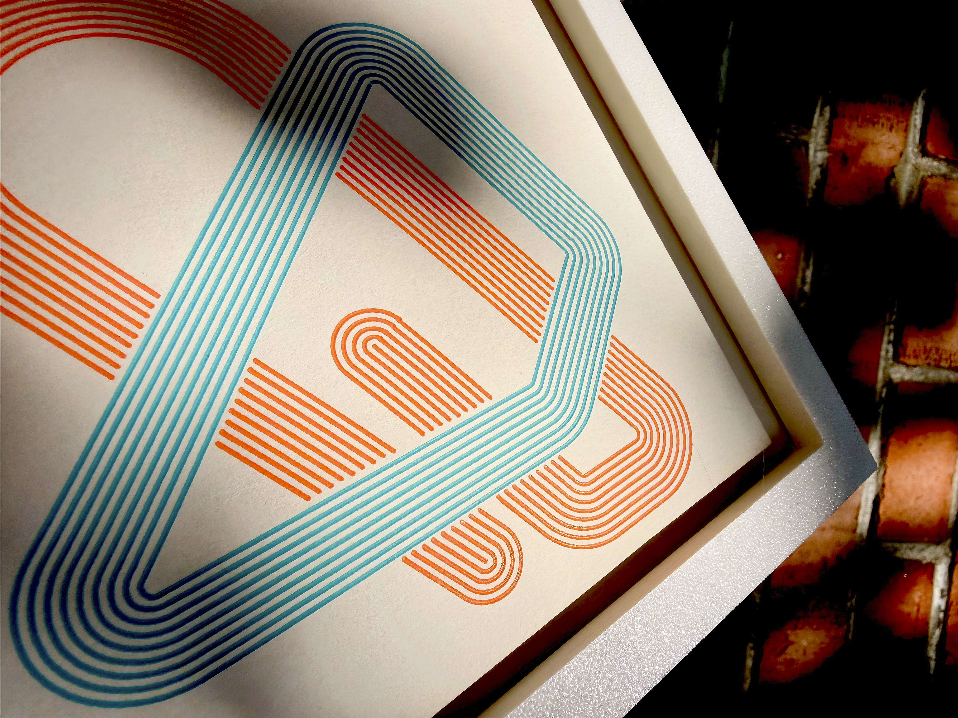 Gerahmte zweifarbige Plotter-Wandkunst in Orange und Türkis — geometrisches Muster aus Rauten und Bögen, Detailaufnahme