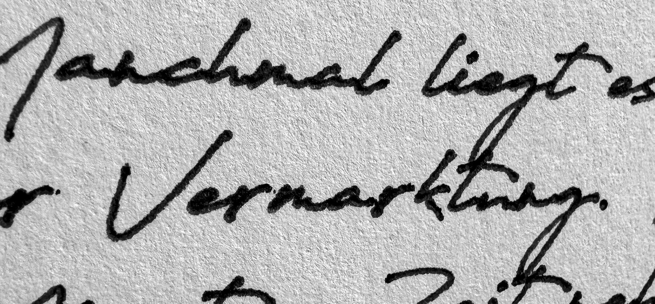 Makroaufnahme handgeschriebener Zeilen mit echtem Stift auf strukturiertem Papier