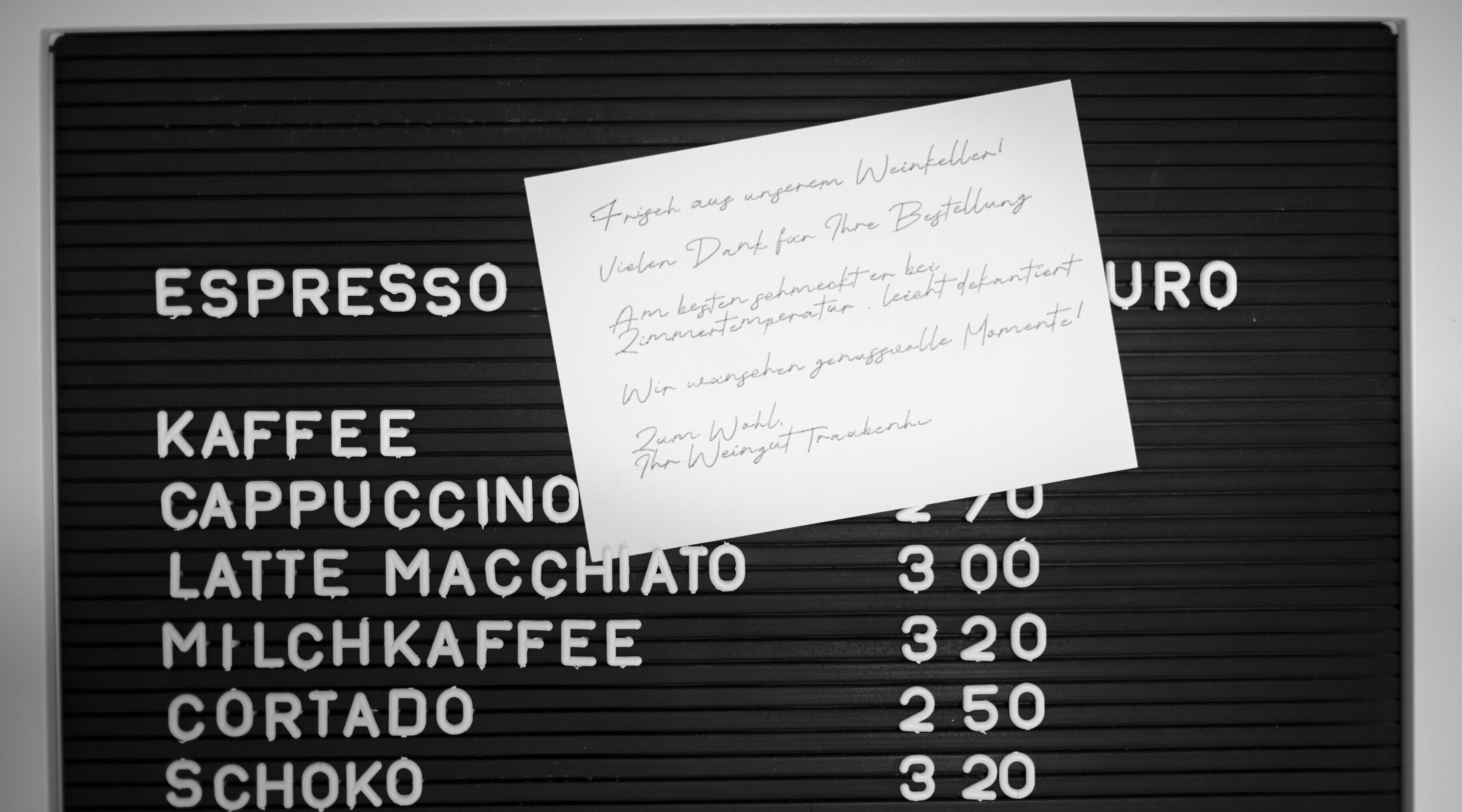 Handgeschriebene Dankeskarte für ein Weingut auf einer Kaffeetafel mit Hinweis zur Serviertemperatur